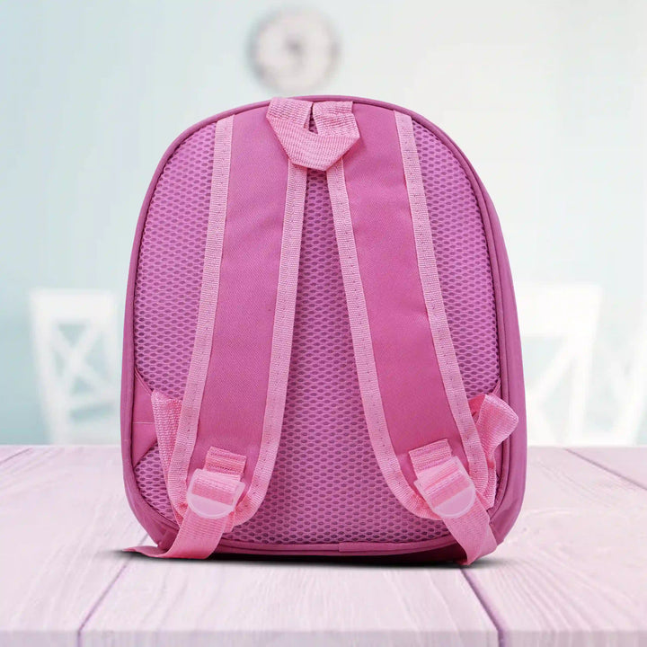 back view of a Pink backpack on a light pink surface with a blurred background
